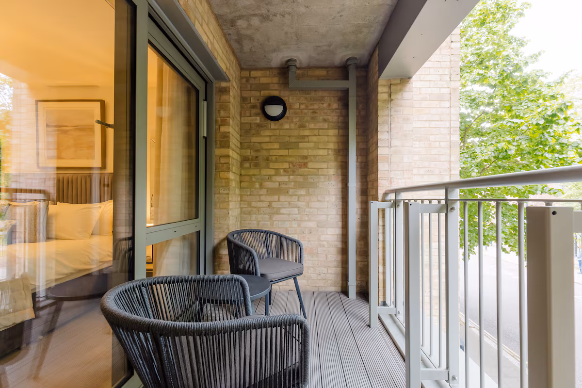 Private balcony with two woven chairs and a side table, opening off the bedroom