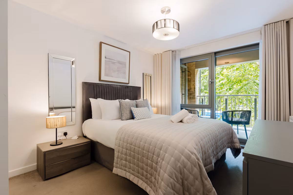 Bedroom with a king bed, framed art and glazed doors onto the private balcony